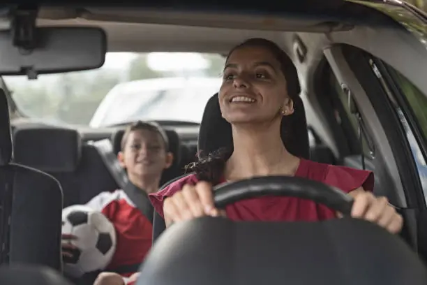 Mamma och barn i bilen på väg till fotbollsträningen
