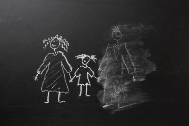Kritteckning på en svart tavla av en familj där en av de vuxna figurerna är till hälften utsuddad