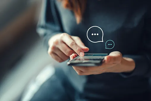 Närbild på en kvinna som skriver på mobilen, med två chattbubblor ovanför skärmen